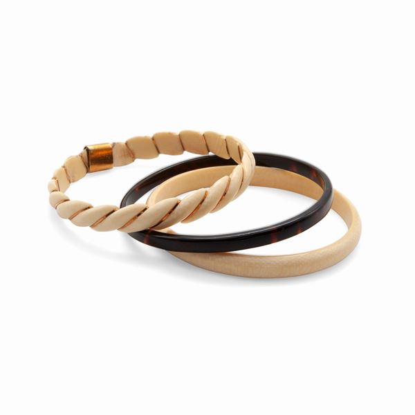 Gruppo di tre bracciali in osso e oro, e bachelite rigidi
