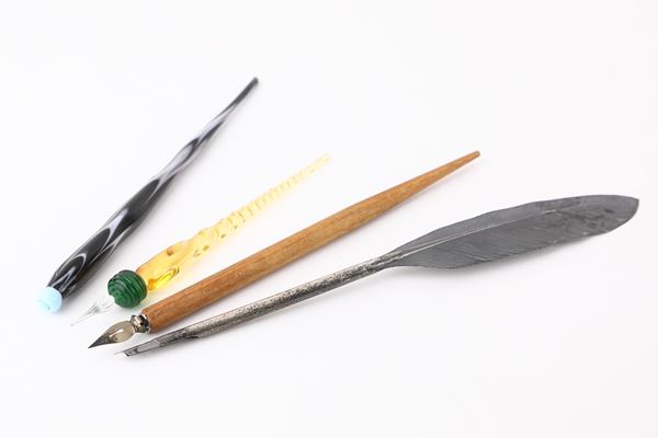 Lotto di quattro oggetti da scrivania: una penna e un tagliacarte in vetro di Murano, una piuma in metallo argentato e una penna in legno con pennino di metallo