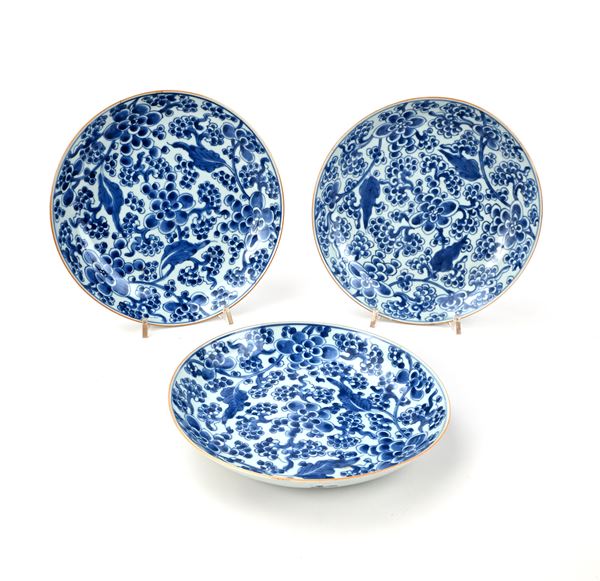 Tre piatti in porcellana bianca e blu con fitta decorazione floreale, Cina, XVIII secolo