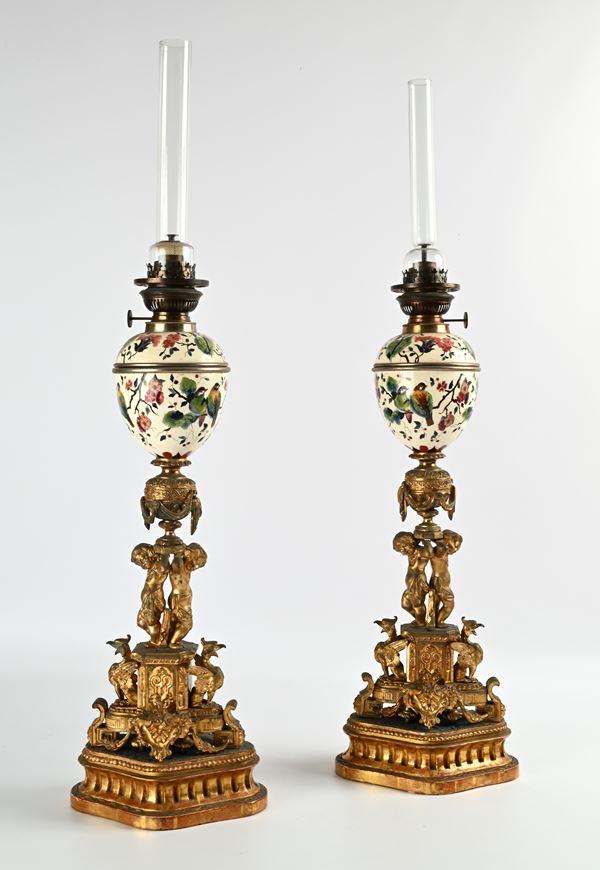 Coppia di lampade ad olio in bronzo e porcellana su base in legno dorato, XIX secolo