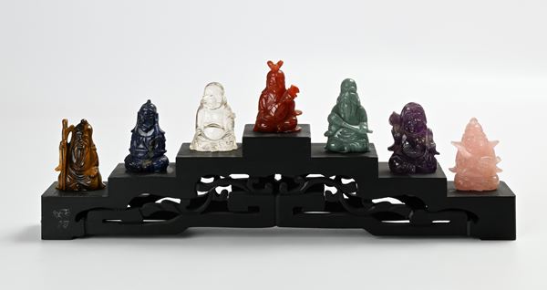 Sette piccole figure di saggio in pietra dura su base gradinata in legno ebanizzato