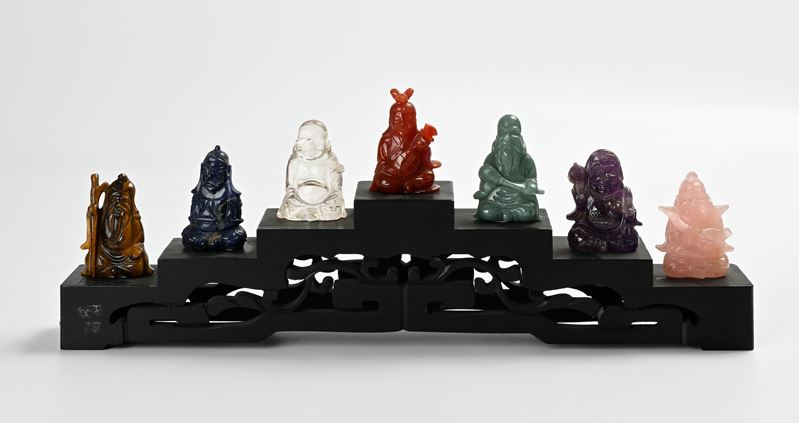 Sette piccole figure di saggio in pietra dura su base gradinata in legno ebanizzato