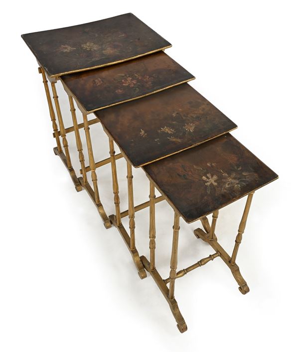 Quattro tavolini a nido in legno dorato con piani rettangolari con fiori dipinti