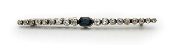 Spilla a barretta in oro, zaffiro centrale e diamanti.