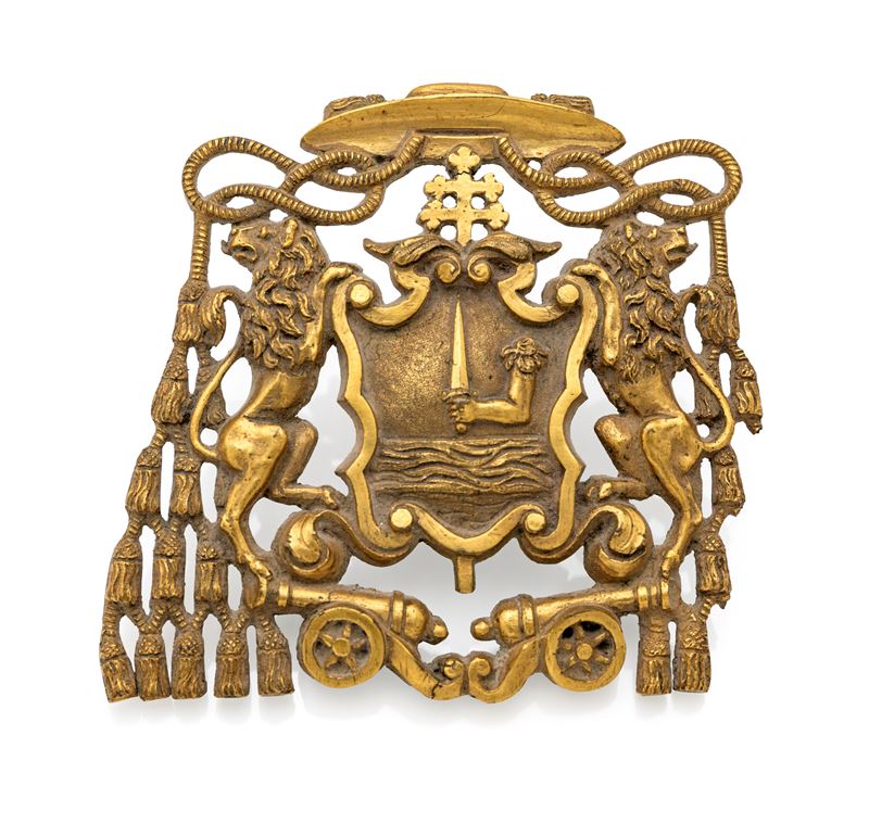 Fregio in bronzo dorato raffigurante uno stemma ecclesiastico con braccio armato di spada, XIX se...