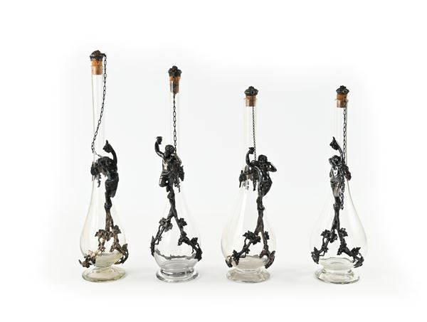 Due coppie di bottiglie in vetro incolore con manici scultorei in metallo argentato, inizi del XX secolo  - Asta Collezioni Private - Mobili, Oggetti d'Arte e Sculture - Casa d'Aste Arcadia
