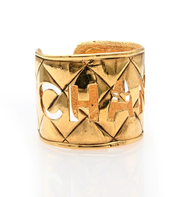 Chanel, bracciale con scritta traforata in metallo dorato 