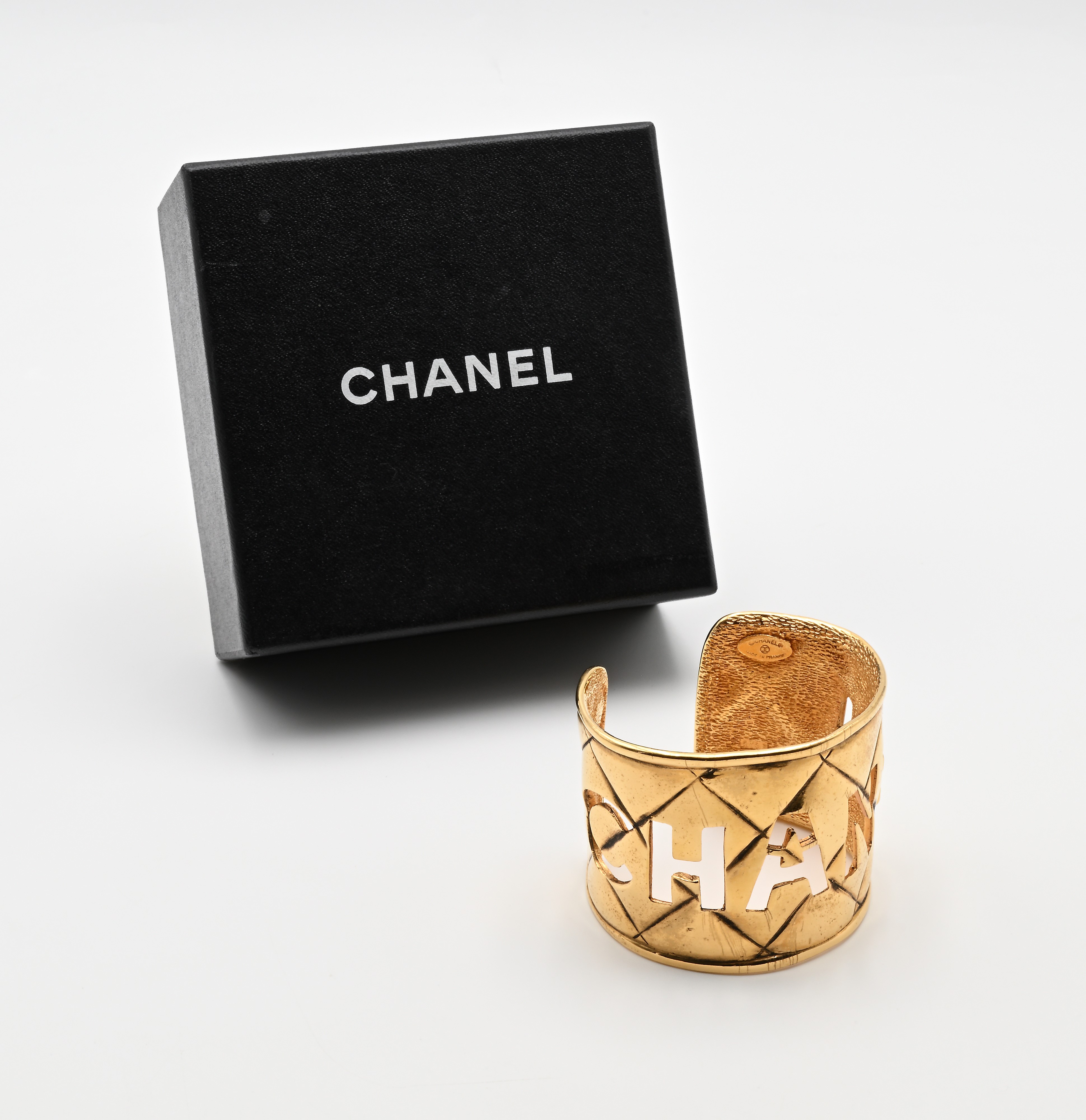 Chanel, bracciale con scritta traforata in metallo dorato